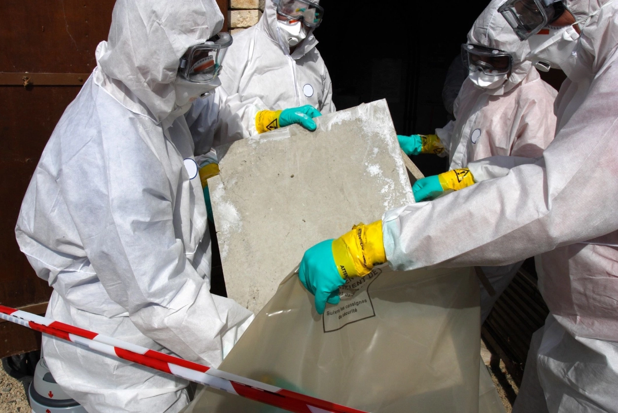 A group of people in hazmat suits holding a piece of metal.