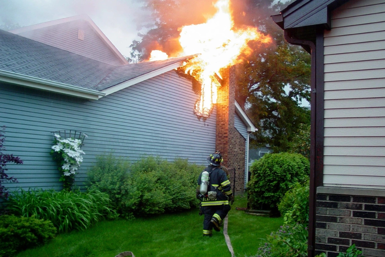 A fireman is in the yard with a hose.